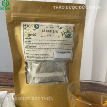 Gói trà lá nam 10 vị túi lọc chuyên hỗ trợ giảm mỡ bụng, bên cạnh ly trà màu vàng nâu đậm đà hương vị thảo mộc.